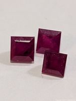 Three square princess-cut rubies on white background