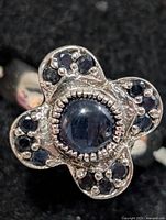 Front view of ring showing cabochon sapphire and surrounding faceted sapphires