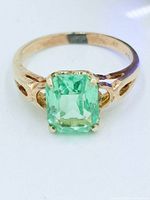 Top view of ring showing emerald-cut green uranium glass stone in four-prong 10k gold setting with open-work shoulders