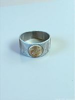 Front view showing engraved silver band and gold medallion