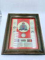 Full view of framed display showing crest, coins and stamps