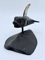 Front left view of argillite killer whale carving showing abalone fin and stone base