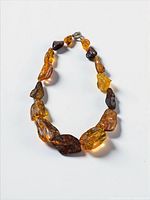 Full view of graduated amber nugget necklace in oval arrangement showing clasp