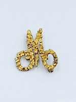 Front view of gold nugget M-shaped brooch
