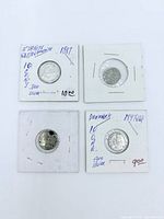 Front of four silver coins in individual flips; handwritten details visible on Straits Settlements and one Denmark coin