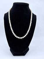 Pearl necklace displayed on black stand