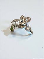 Full view of coiled snake ring with dangling peridot