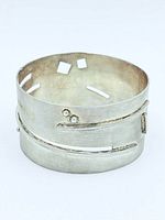 Wide sterling silver cuff bracelet front view showing linear cutouts and raised accents