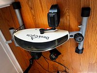 Top view of DeskCycle pedal exerciser showing brand logo, pedals, resistance dial, stabilizer bars