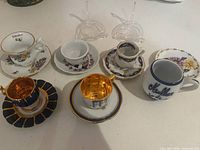 Group of miniature porcelain cups, saucers, mug and stands