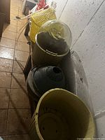 Row of winemaking vessels and accessories including glass demijohn, baskets, drying rack