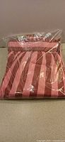 Sealed pink and burgundy striped lounge pants folded in bag