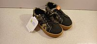 pair of camouflage sneakers size 12, angled view with tag visible