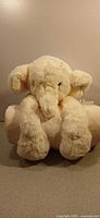 Elephant plush toy sitting on rolled blanket, frontal view