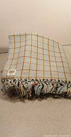 Folded plaid cotton throw blanket showing fringe and pattern