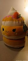 Front view of large Sawtelle Squishmallows plush showing face, whipped cream, fruit accent and hang tag