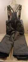 Full view of dark gray boys snow pants with suspenders