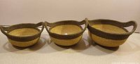 Three nested two-tone jute baskets side by side