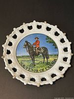 Front view of plate showing Mountie scene and pierced rim