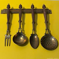 Set of four brass utensils hanging on rack