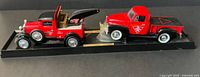 Full view of 1929 Ford Model A tow truck and 1952 Chevy pickup on display base