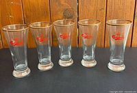 Front view of five matching Carlsberg fluted glasses with logo and gold rim