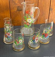 Front view of pitcher and six tumblers displaying floral designs