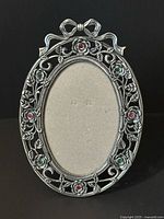 Front view of silver-tone oval frame showing floral design and rhinestone accents