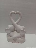 Front view of white ceramic elephant sculpture showing heart-shaped trunks
