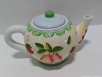 Left side view of teapot showing raised fruit decoration and lid