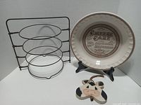 Full lot showing pie plate on easel, three-tier rack, cow ornament