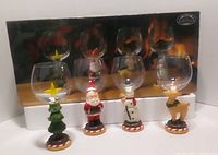 Boxed set showing four wine goblets with holiday character bases