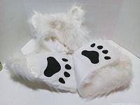 White faux fur hood with bear ears and attached scarf ends showing black paw prints
