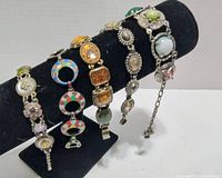 Four vintage charm bracelets displayed on black stand