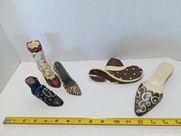 All five decorative shoe items laid flat with measuring tape for scale