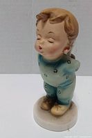 Front view of porcelain boy figurine showing facial details, pajama pattern and base
