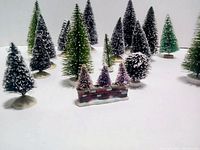 Group of miniature Christmas village trees on white background