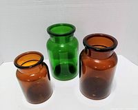 Three colored glass jars upright against white backdrop