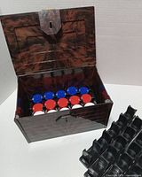 Open tortoise-shell pattern box showing interior chip rack filled with red, white, blue chips and separate black chip trays