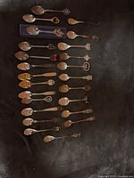 Full group of 24 assorted souvenir spoons displayed