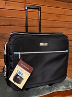 Front view of black Recollections rolling tote with hang tag and telescopic handle