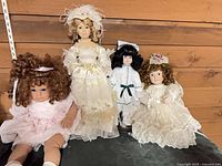 Four dolls displayed side by side on shelf
