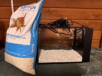 Glass aquarium with gravel bag beside it