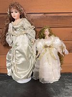 Both porcelain dolls side by side against wood backdrop