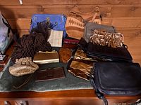 Wide view of assorted handbags, clutches and wallets on green surface