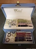 Open box showing watch, bezels and straps in two tiers