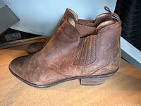 Side view of brown suede Bass ankle boot showing upper, elastic gore, pull tab, and heel.