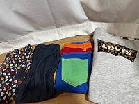 Four of five garments folded: heart leggings, navy leggings, color-block pants, Levi’s sweatshirt