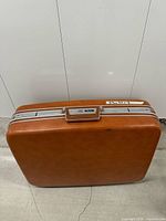 Front view of large burnt orange Jetliner hard suitcase