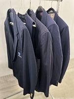 Four navy blue jackets on rack, showing variety and embroidered logo